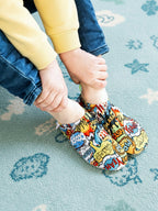 Chaussons d'eau motifs comics portés par un enfant en intérieur