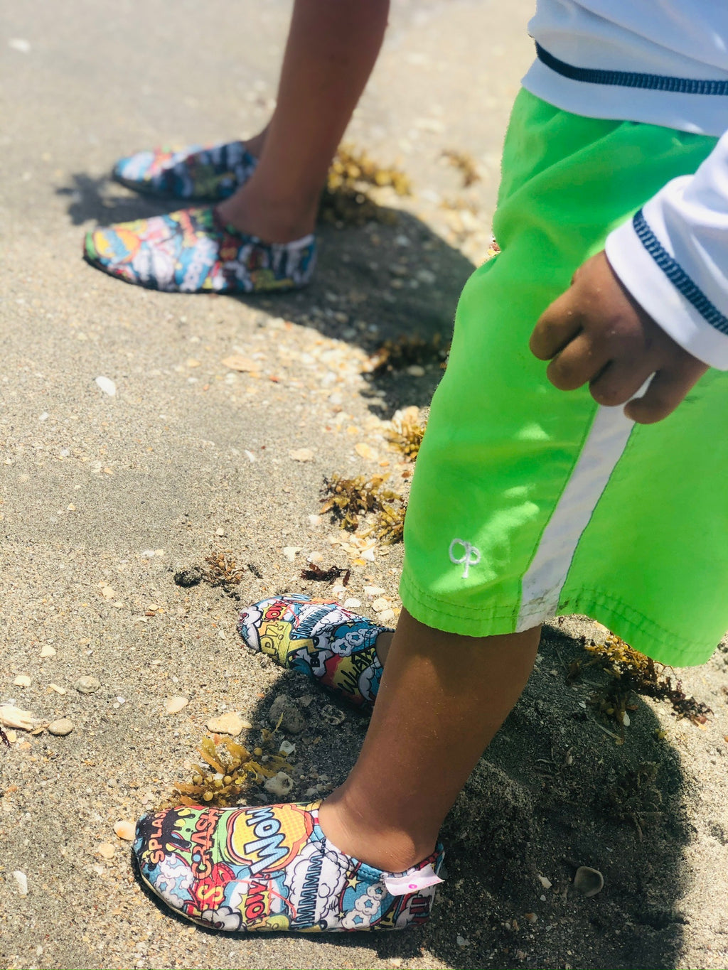Chaussons d'eau motifs comics portés par un enfant à la plage