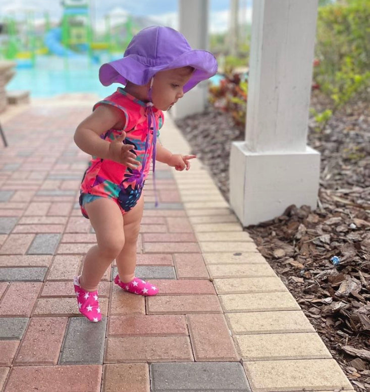 Chaussons d'eau rose motifs étoiles portés par un enfant sur une terrasse