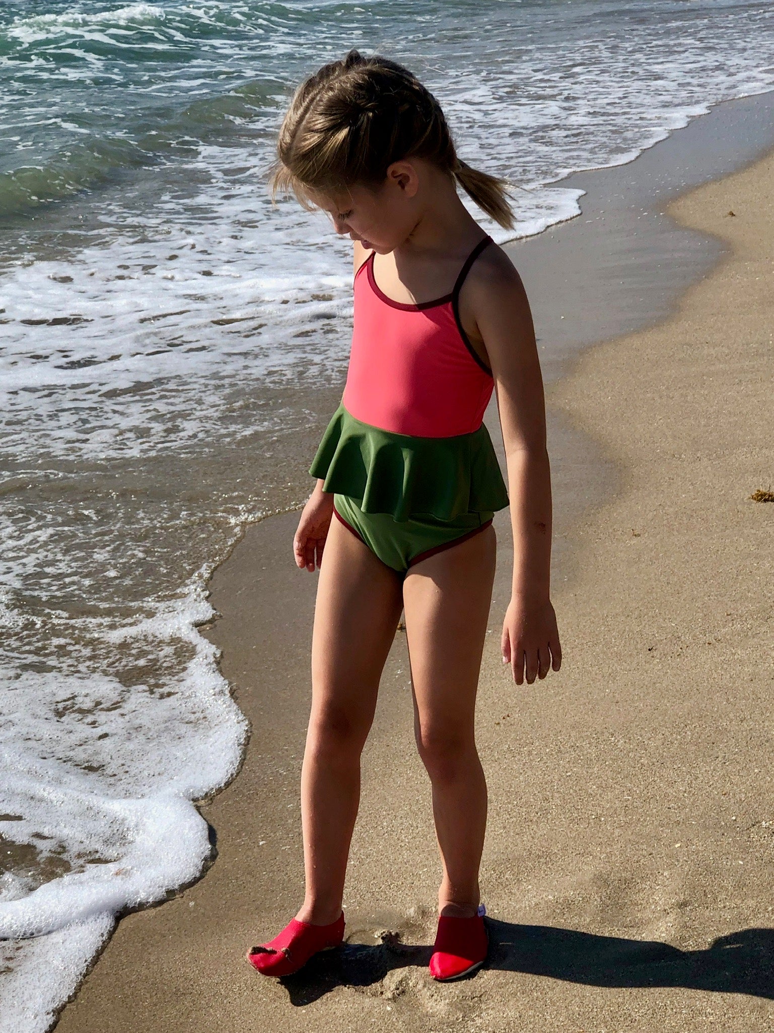 Chaussons d'eau rouges portés par un enfant au bord de la plage
