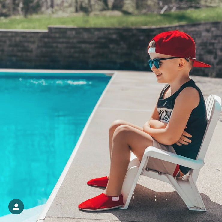 Chaussons d'eau rouges portés par un enfant au bord de la piscine