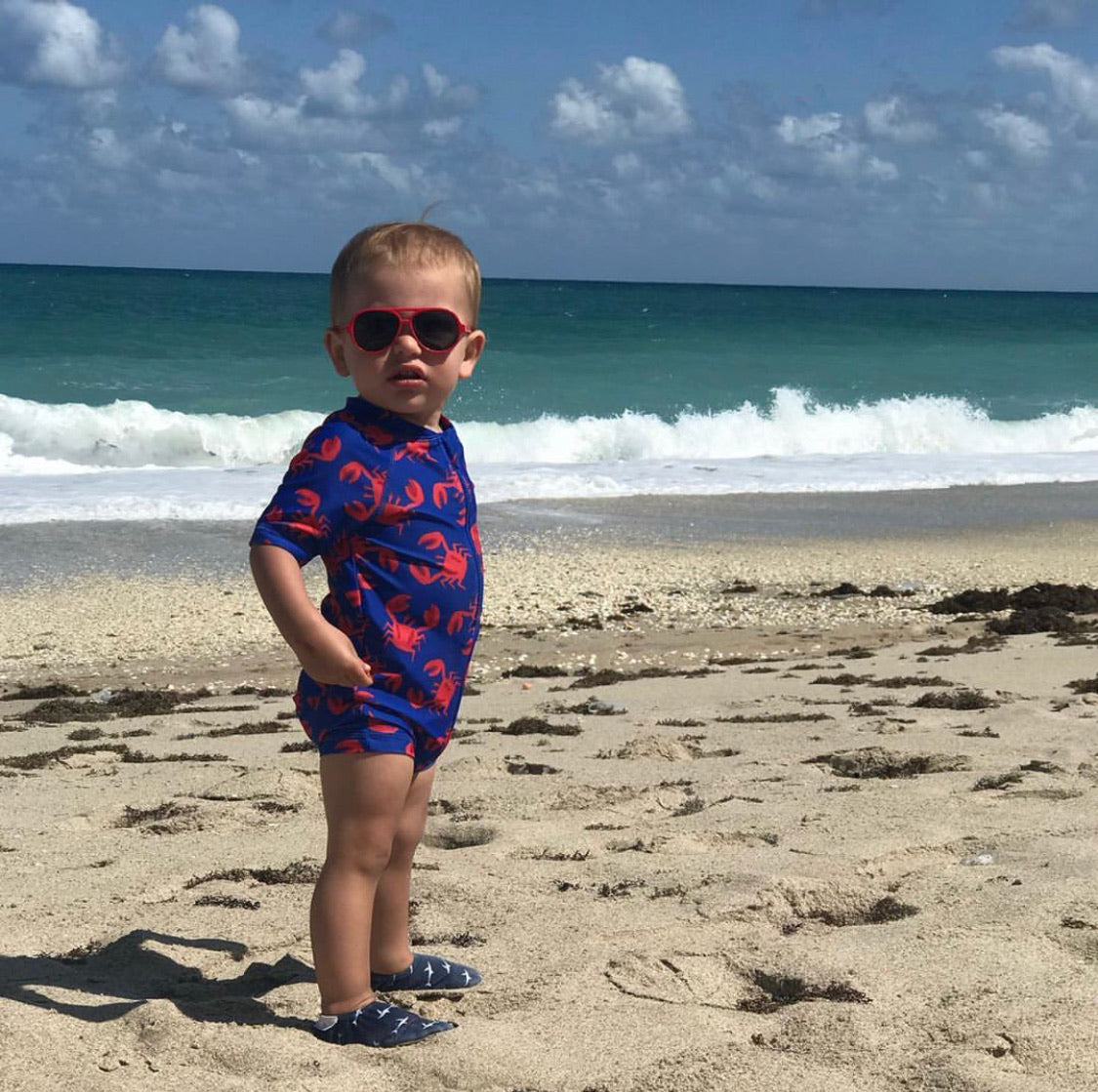 Chaussons d'eau motifs requins portés par un enfant à la plage